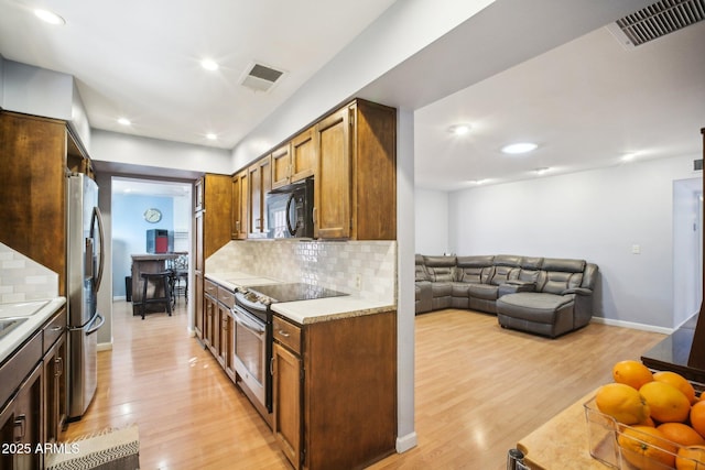 kitchen featuring decorative backsplash, light hardwood / wood-style flooring, and appliances with stainless steel finishes