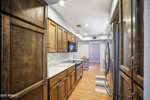 kitchen with stainless steel appliances, light hardwood / wood-style floors, and decorative backsplash