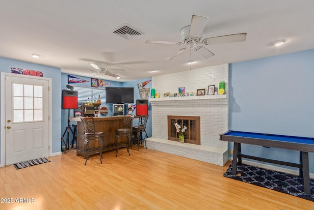 bar with pool table, hardwood / wood-style flooring, ceiling fan, and a brick fireplace