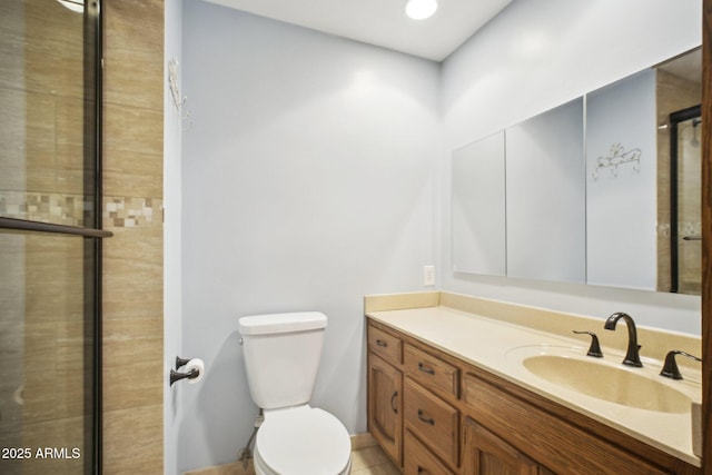 bathroom with toilet, vanity, and a shower with shower door