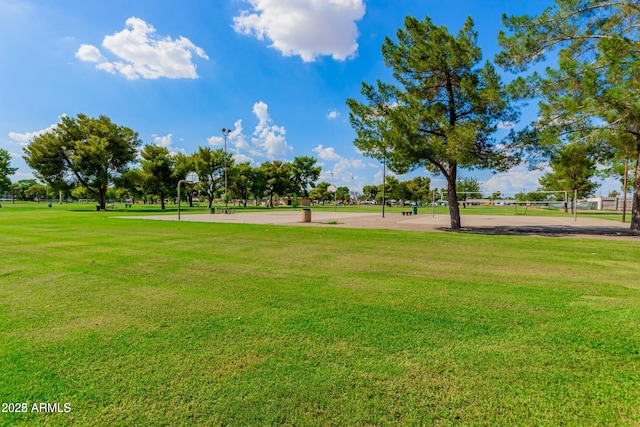 view of community with basketball hoop, volleyball court, and a lawn