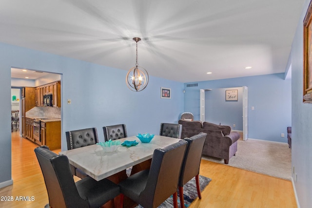 dining room with light wood-type flooring and an inviting chandelier