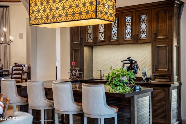 27256 N 97th Pl, Scottsdale, AZ 85262 - bar with dark brown cabinetry, sink, decorative backsplash, and a notable chandelier