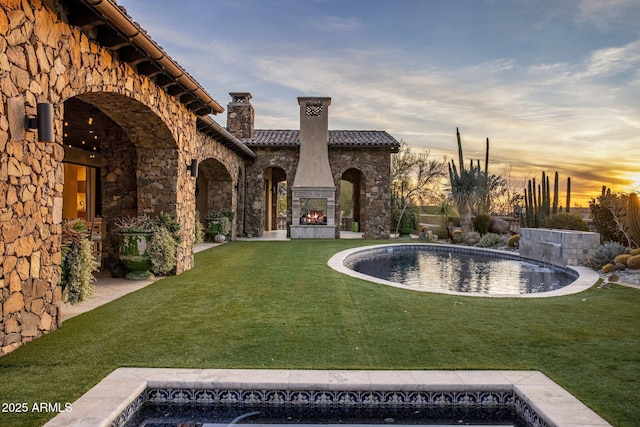 27256 N 97th Pl, Scottsdale, AZ 85262 - pool at dusk with an outdoor fireplace and a lawn