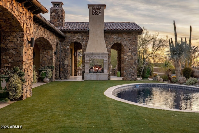 27256 N 97th Pl, Scottsdale, AZ 85262 - back house at dusk featuring a yard and an outdoor stone fireplace