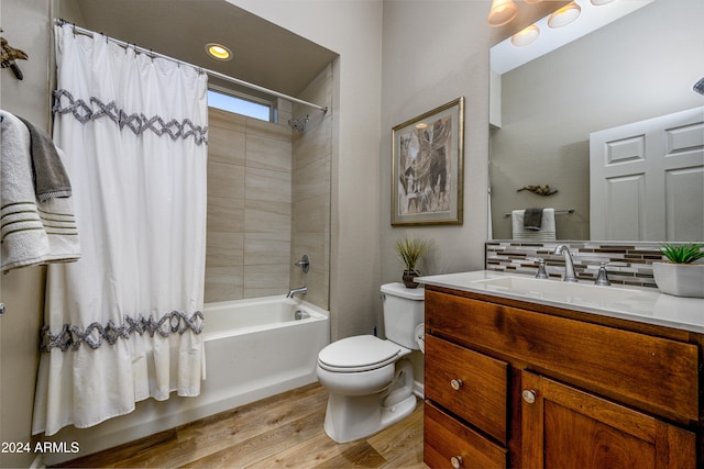 full bathroom featuring toilet, wood-type flooring, vanity, shower / bath combo with shower curtain, and tasteful backsplash