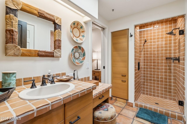 bathroom with tile patterned floors, vanity, and a tile shower