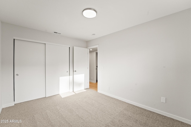unfurnished bedroom featuring carpet floors, baseboards, visible vents, and a closet