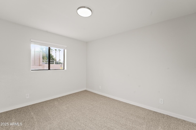 carpeted empty room featuring baseboards
