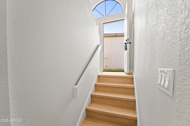 staircase featuring a textured wall and wood finished floors