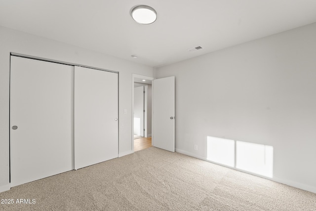 unfurnished bedroom featuring carpet floors, visible vents, and a closet