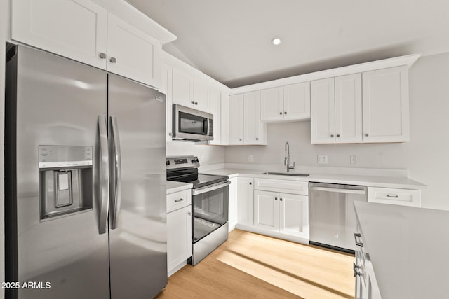 kitchen featuring a sink, light countertops, white cabinets, light wood finished floors, and stainless steel appliances
