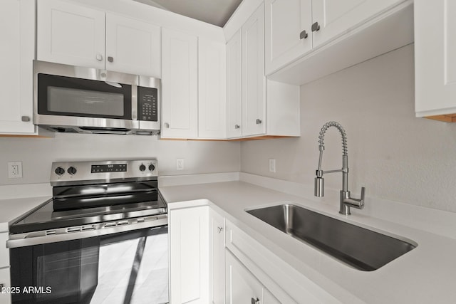 kitchen featuring light countertops, stainless steel appliances, white cabinets, and a sink