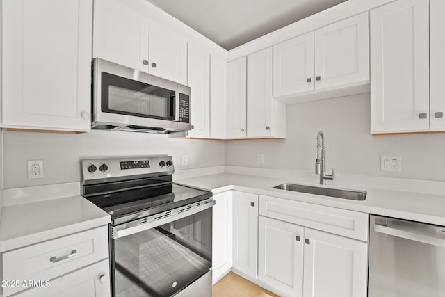 kitchen featuring a sink, appliances with stainless steel finishes, white cabinets, and light countertops