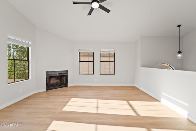 unfurnished living room with baseboards, a fireplace, a ceiling fan, and light wood finished floors