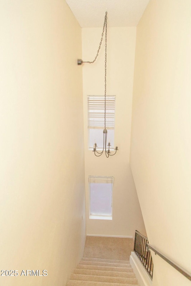 stairs with carpet flooring and an inviting chandelier