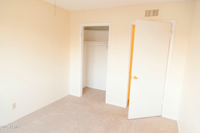 unfurnished bedroom with light carpet and a closet