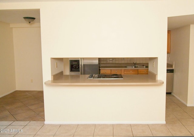 kitchen featuring sink, light tile patterned floors, black electric cooktop, and kitchen peninsula