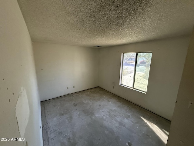 unfurnished room featuring a textured ceiling and concrete floors