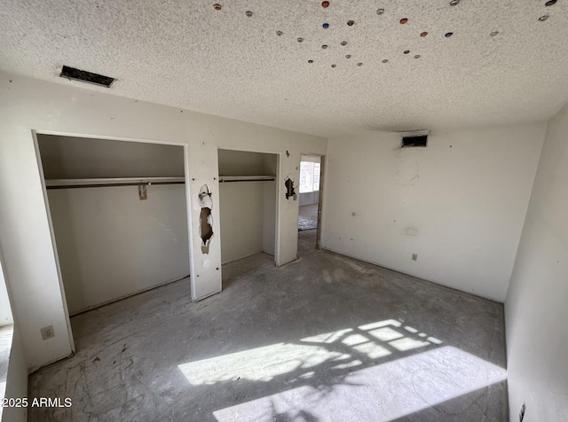 unfurnished bedroom featuring two closets and a textured ceiling