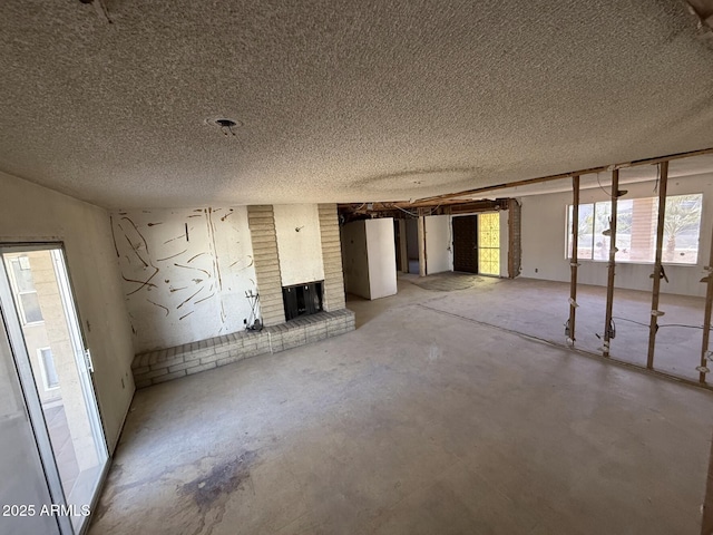 empty room with concrete flooring, a textured ceiling, and a fireplace