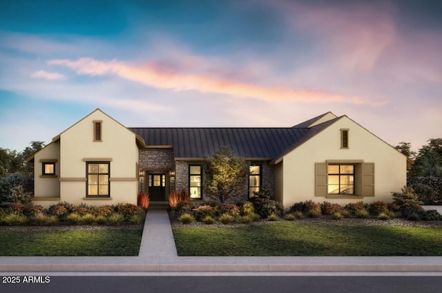 modern inspired farmhouse with stucco siding, a standing seam roof, metal roof, stone siding, and a front lawn