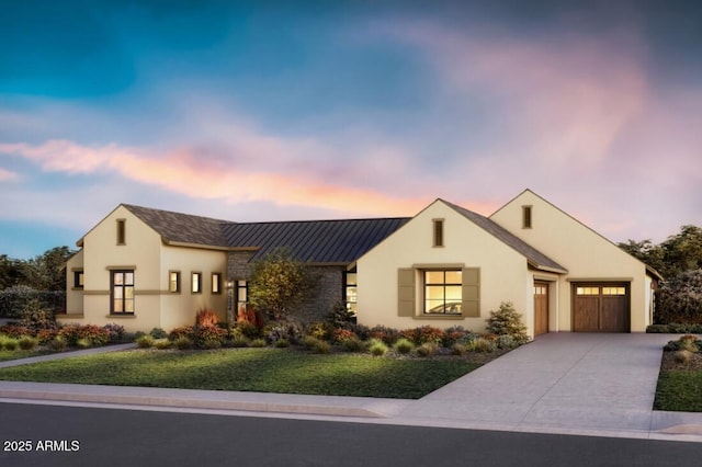 view of front of home with metal roof, an attached garage, concrete driveway, stucco siding, and a standing seam roof