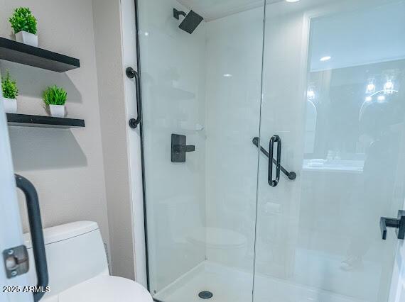 bathroom featuring a shower with door and toilet