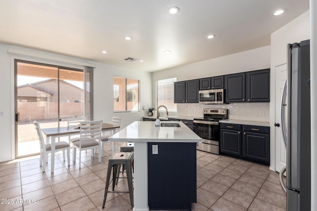 kitchen featuring visible vents, light countertops, appliances with stainless steel finishes, a kitchen bar, and a center island with sink