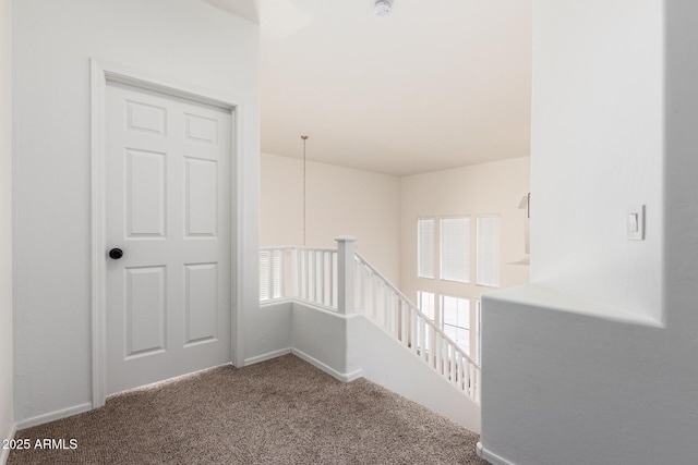 hall with carpet, baseboards, a healthy amount of sunlight, and an upstairs landing