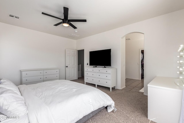 carpeted bedroom with arched walkways, visible vents, ceiling fan, and baseboards