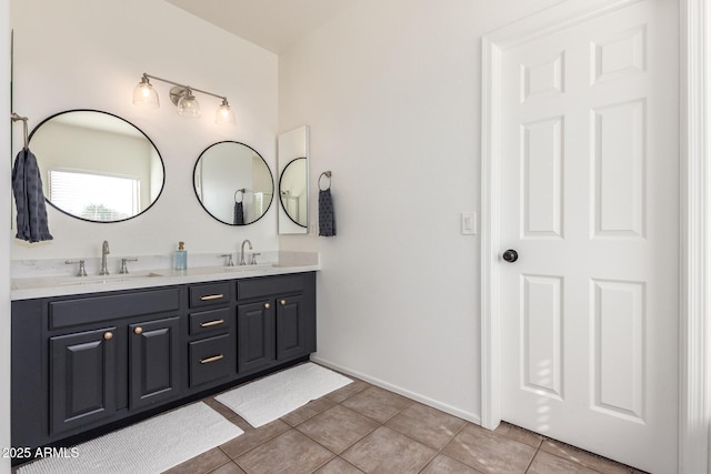 full bathroom featuring double vanity, baseboards, a sink, and tile patterned floors