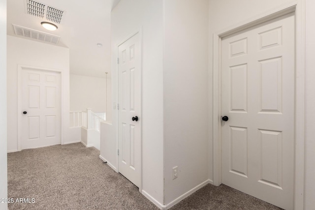 corridor with carpet, visible vents, and baseboards