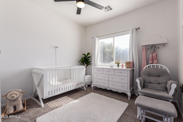 bedroom featuring visible vents, dark carpet, a crib, and ceiling fan