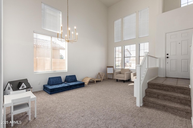 interior space featuring a towering ceiling, an inviting chandelier, stairs, and carpet flooring