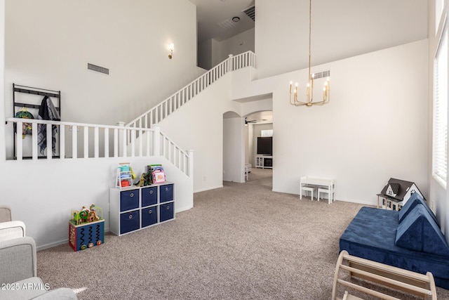 interior space featuring arched walkways, carpet, visible vents, stairway, and a high ceiling