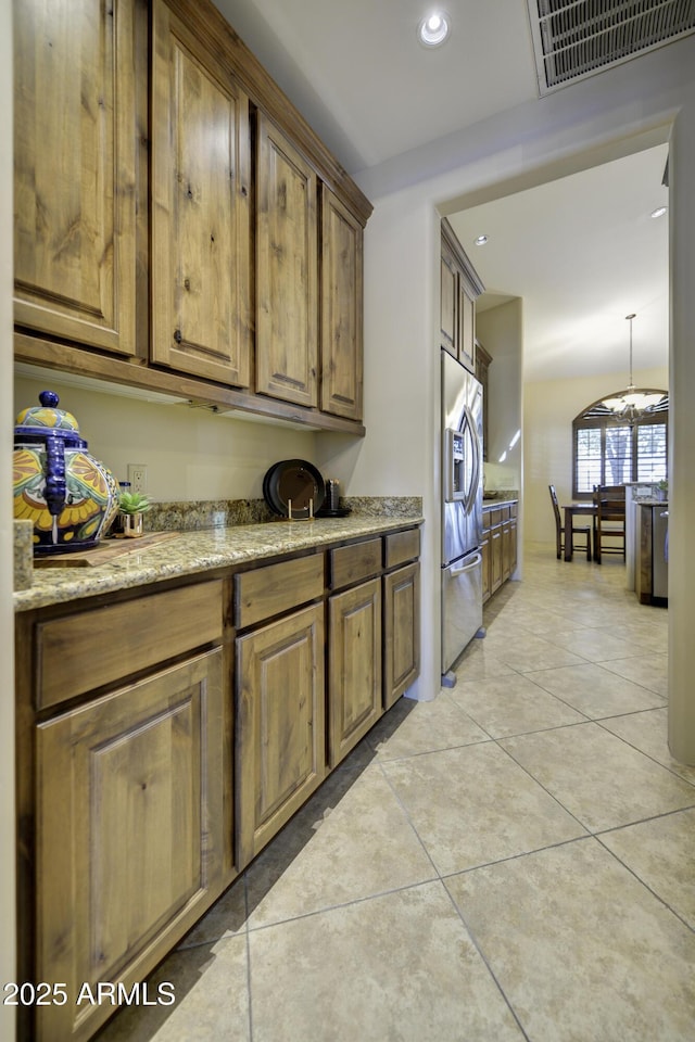 kitchen featuring stainless steel refrigerator with ice dispenser, light stone countertops, and light tile patterned flooring