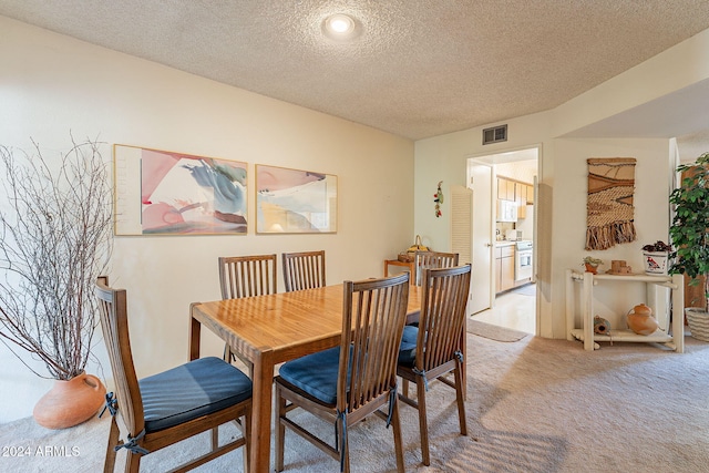 carpeted dining room featuring a textured ceiling