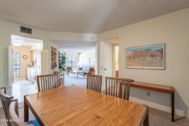 carpeted dining room with a textured ceiling