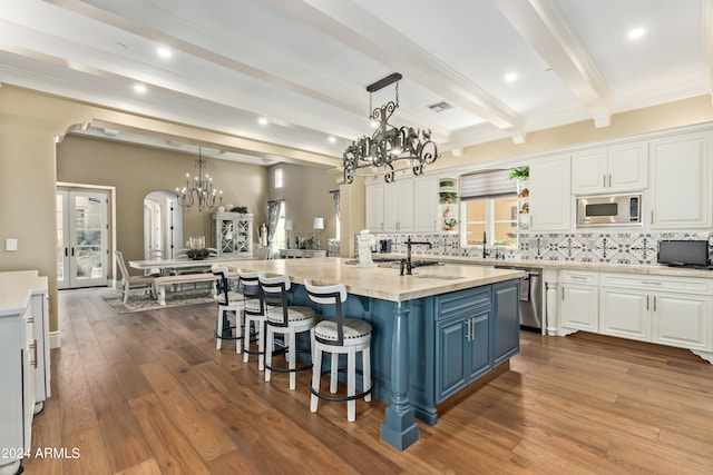 kitchen featuring light stone countertops, a center island with sink, stainless steel appliances, and tasteful backsplash