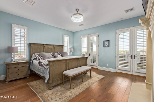 bedroom featuring access to exterior, wood-type flooring, multiple windows, and french doors