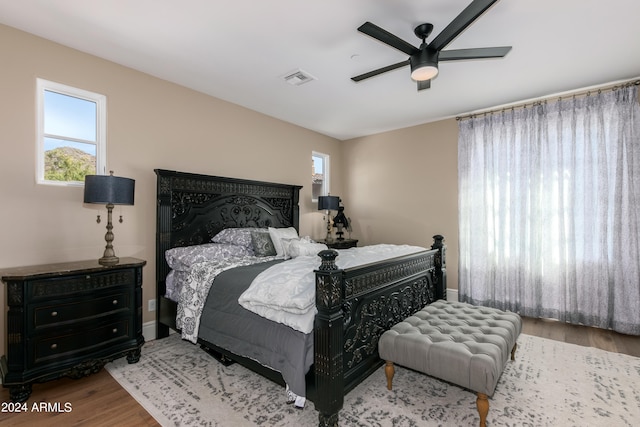 bedroom featuring ceiling fan, hardwood / wood-style floors, and multiple windows