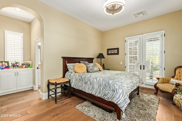 bedroom featuring access to exterior, light hardwood / wood-style flooring, and french doors