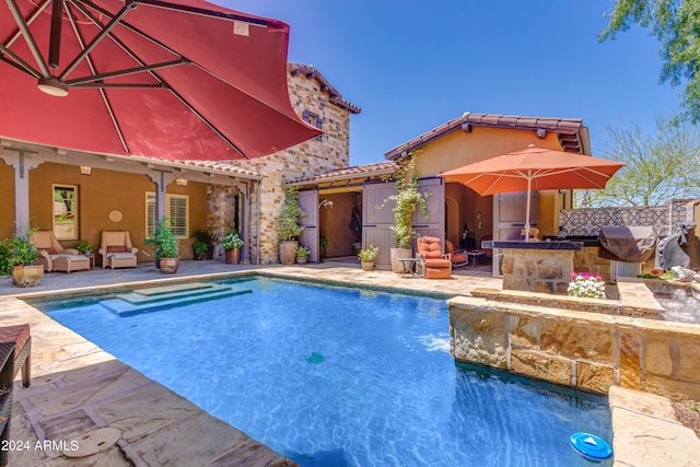 view of swimming pool with exterior kitchen, a bar, and a patio area