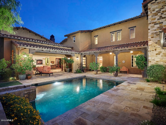 pool at dusk with a patio area