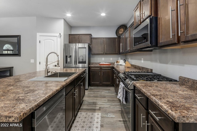 kitchen featuring dark countertops, dark brown cabinets, appliances with stainless steel finishes, and a sink