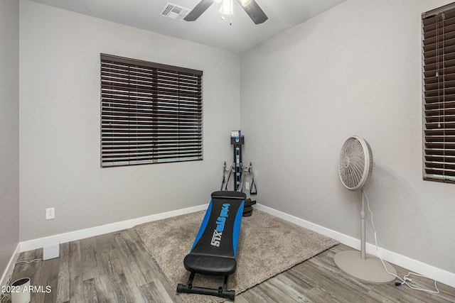 exercise room featuring visible vents, a ceiling fan, baseboards, and wood finished floors