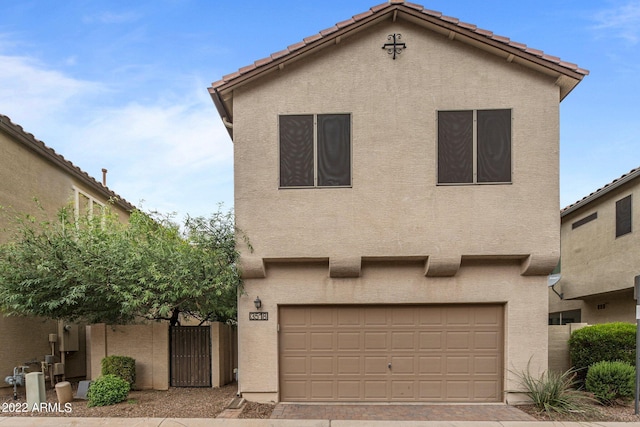 view of front facade featuring decorative driveway, a tiled roof, an attached garage, and stucco siding