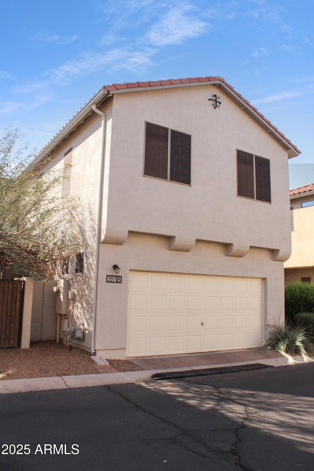 view of front of house with stucco siding, a garage, and fence