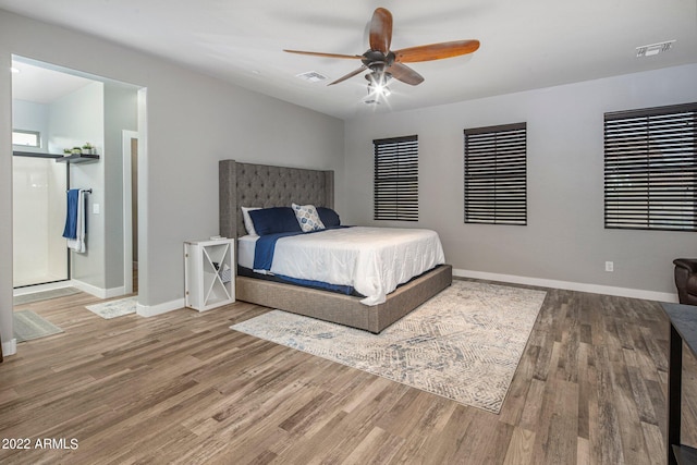 bedroom featuring a ceiling fan, wood finished floors, visible vents, and baseboards